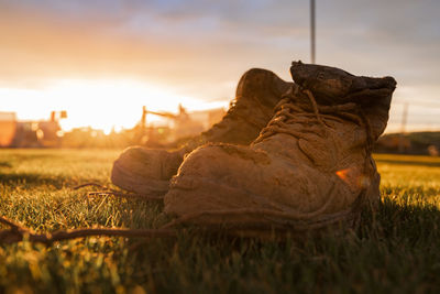 Close-up of shoes on field during sunset