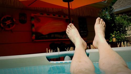 Low section of person relaxing in swimming pool at yard