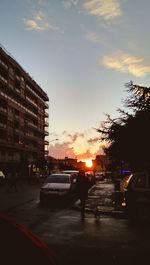 Silhouette of vehicles on road against sunset sky