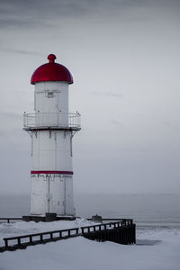 Lighthouse by sea against sky