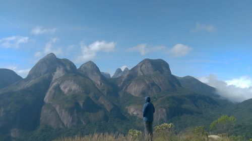 Rear view of man standing on mountain against sky