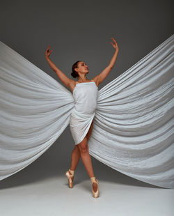 Full length of young woman standing against curtain