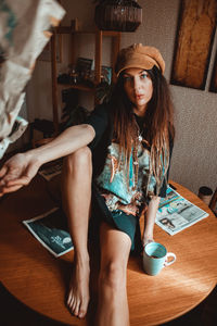 High angle portrait of woman sitting on table at home