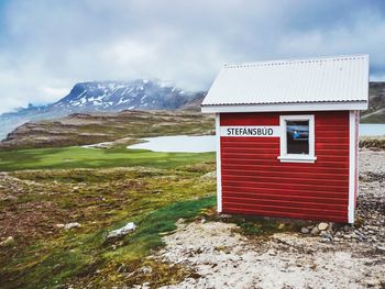 Built structure on field against snowcapped mountains