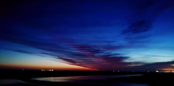 Scenic view of sea against dramatic sky at sunset