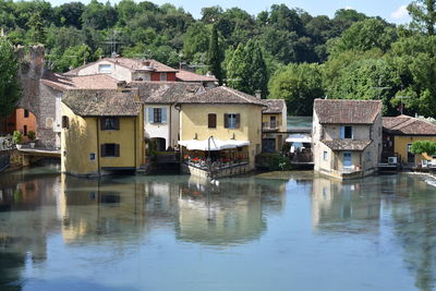 Buildings by lake against trees