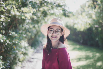 Portrait of smiling young woman against trees