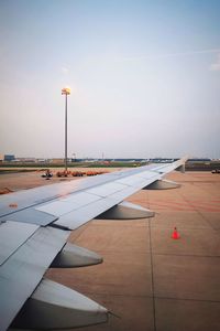 Airplane on airport runway against sky during sunset