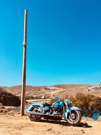 Bicycle parked on desert land against clear blue sky