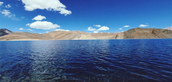 Scenic view of sea and mountains against blue sky