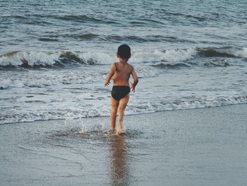 Full length of shirtless boy standing on beach