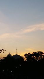 Silhouette trees and buildings against sky during sunset