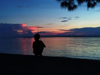 Silhouette man on beach against sky during sunset