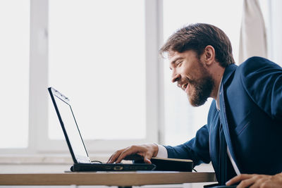 Side view of man using laptop at home