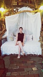 Portrait of a smiling young woman sitting on bed