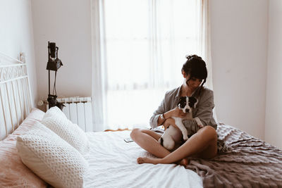 Woman sitting on bed at home