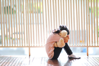 Side view of girl sitting on seat at home