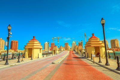 Street amidst buildings against blue sky