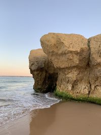 Rock formation on beach against clear sky
