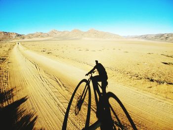 Shadow of man riding bicycle on desert