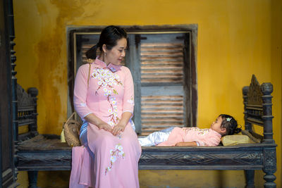Mother and daughter with vietnam culture traditional dress sitting at ancient town hoi an.