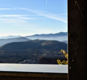 Close-up of spider web on window against sky