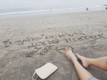 Low section of woman on beach against sky