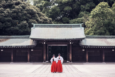 Rear view of people walking in temple outside building