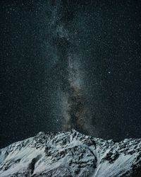 Scenic view of snowcapped mountain against sky at night