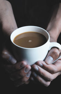 Midsection of man holding coffee cup