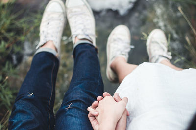 Low section of couple holding hands outdoors