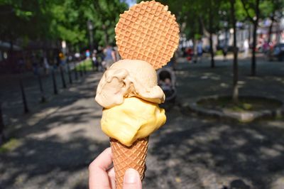 Cropped hand holding ice cream cone in city