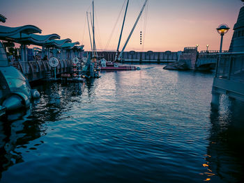 Boats moored in harbor at sunset