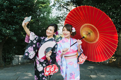 Woman photographing with umbrella standing against the wall