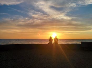 Scenic view of two people at sea during sunset