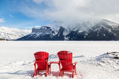 Chair on snowcapped mountains against sky