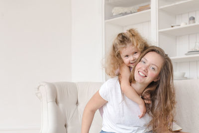 Portrait of smiling mother and daughter embracing at home