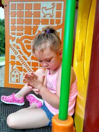 Girl sitting on slide at playground