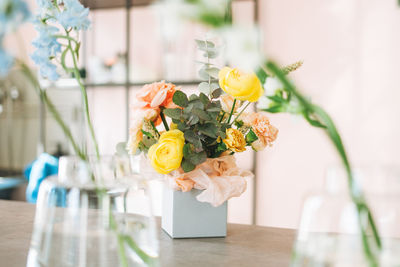 Flower arrangement with yellow and pink roses and eucalyptus in the gift box on table in flower shop