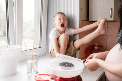 Midsection of pregnant mother preparing food with son at home