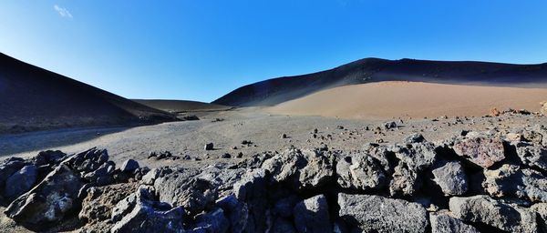 Panoramic view of arid landscape against clear blue sky