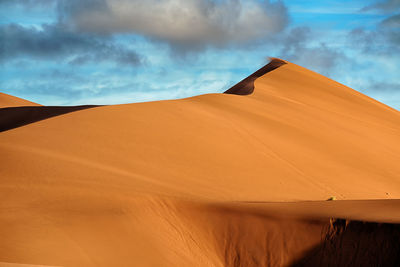 Scenic view of desert against cloudy sky