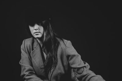 Portrait of beautiful young woman against black background