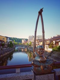 Statue by river against buildings in city