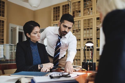 Lawyer discussing with female coworkers at table in meeting