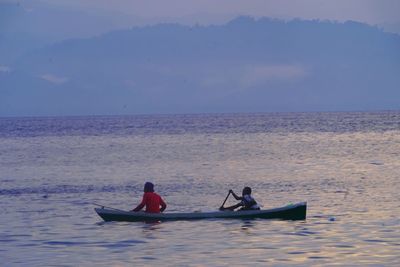 People on boat in sea against sky