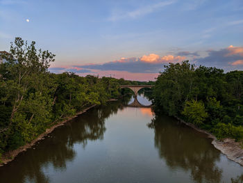 Arch bridge over river against sky during sunset