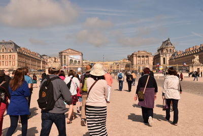 Rear view of tourists walking towards chateau de versailles
