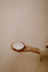 Person holding fruit against wall