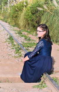 Full portrait of a girl sitting on a railroad tie